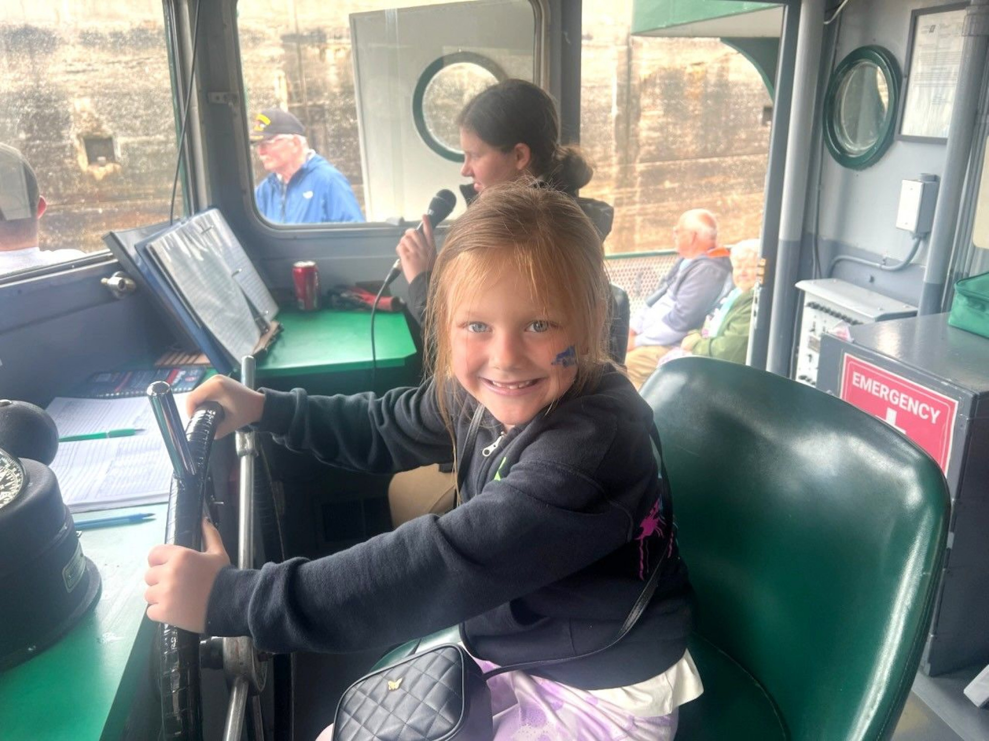 Kids having fun at the helm on the Original Soo Locks Boat Tours during Little Sailors Day Kids Ride Free maritime family event in Michigan's Upper Peninsula