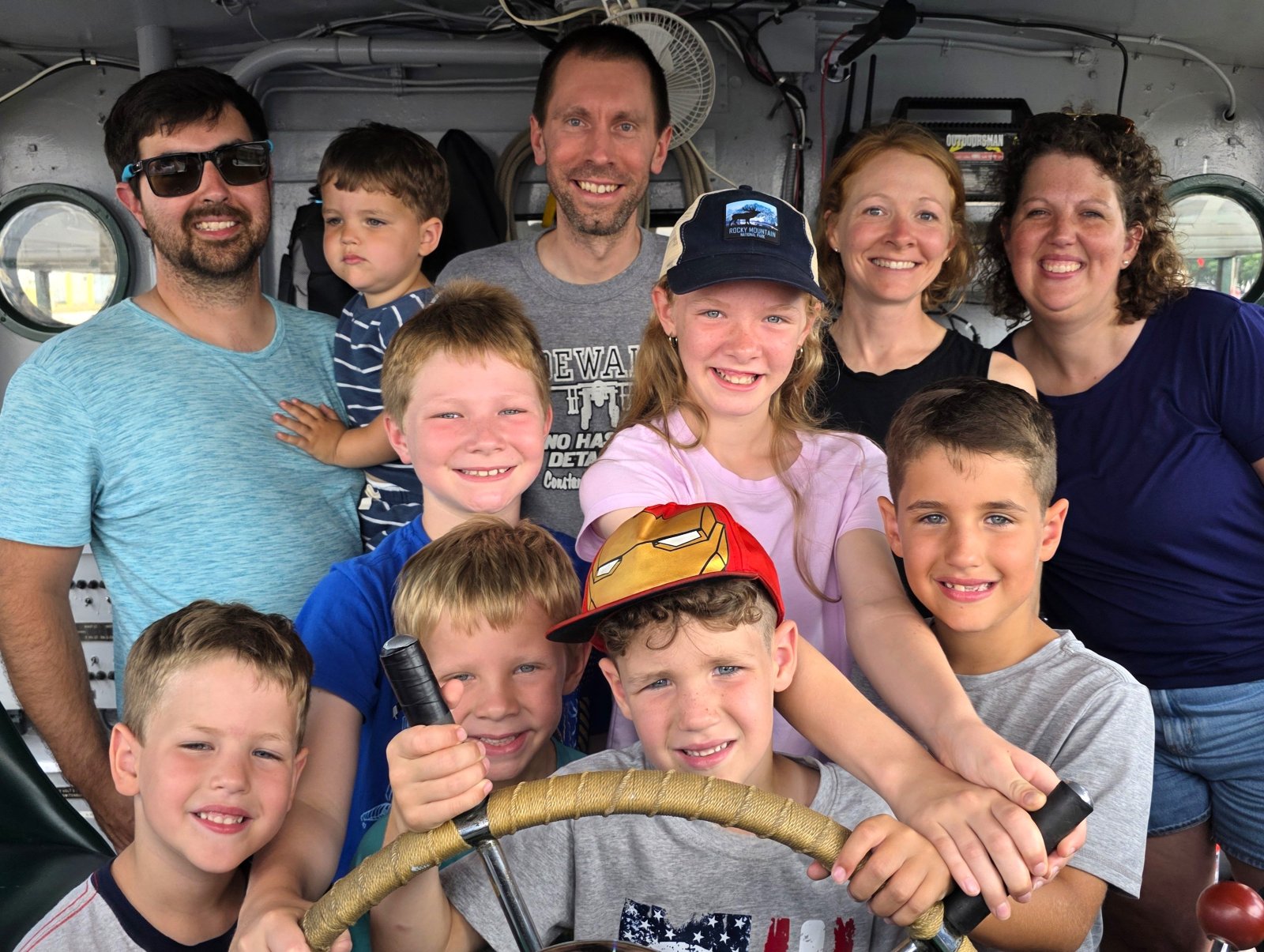 Family smiling and having fun at the helm aboard the Original Soo Locks Boat Tours in Michigan's Upper Peninsula Sault Ste. Marie