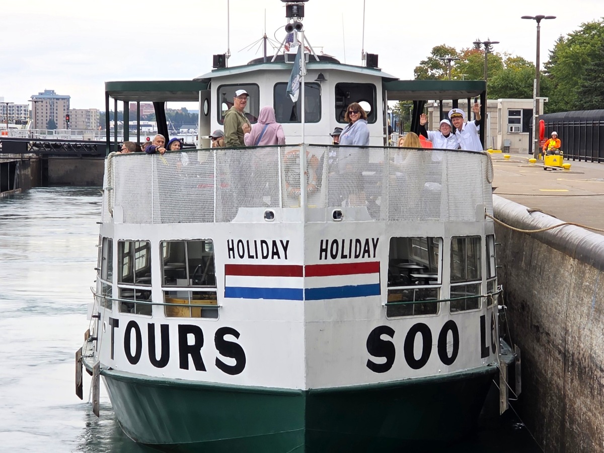 A Soo Locks tour boat entering the lock chamber with passengers on board, showing the live lock-through experience in Sault Ste. Marie, Michigan.