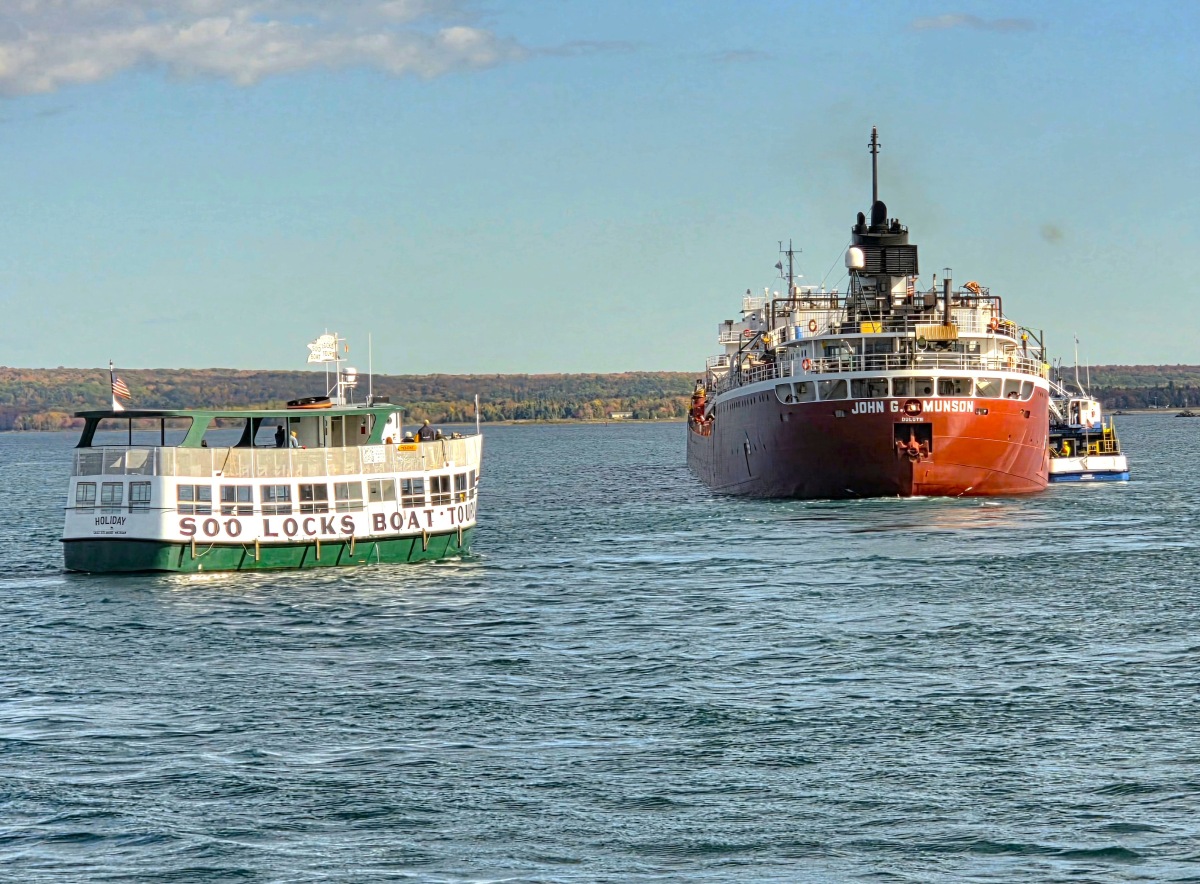 The Soo Locks tour boat Holiday cruising near the Great Lakes freighter John G. Munson on the St. Marys River in Sault Ste. Marie, Michigan.