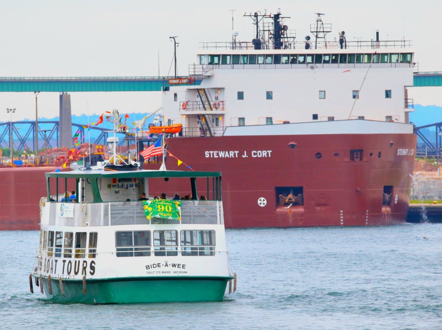 Guest on board the Soo Locks Tours Boat Bid-A-Wee up close to the freighter Stewart J. Cort coming out of the Poe Lock Sault Michigan