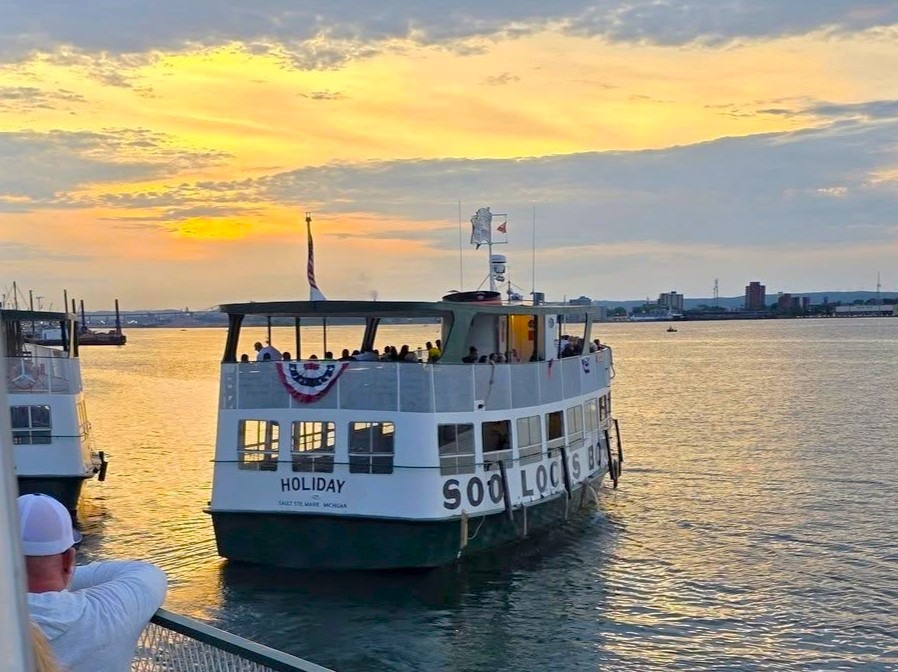 Original Soo Locks Tours Boats departing dock into a beautiful sunset during their firework cruises in Sault Ste. Marie Upper Peninsula of Michigan