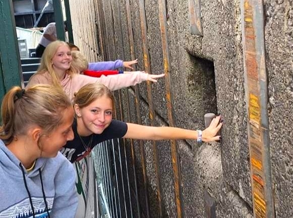 Children reaching out toward the lock wall during an interactive moment on a Soo Locks boat tour, demonstrating how close the vessel travels through the lock chamber.