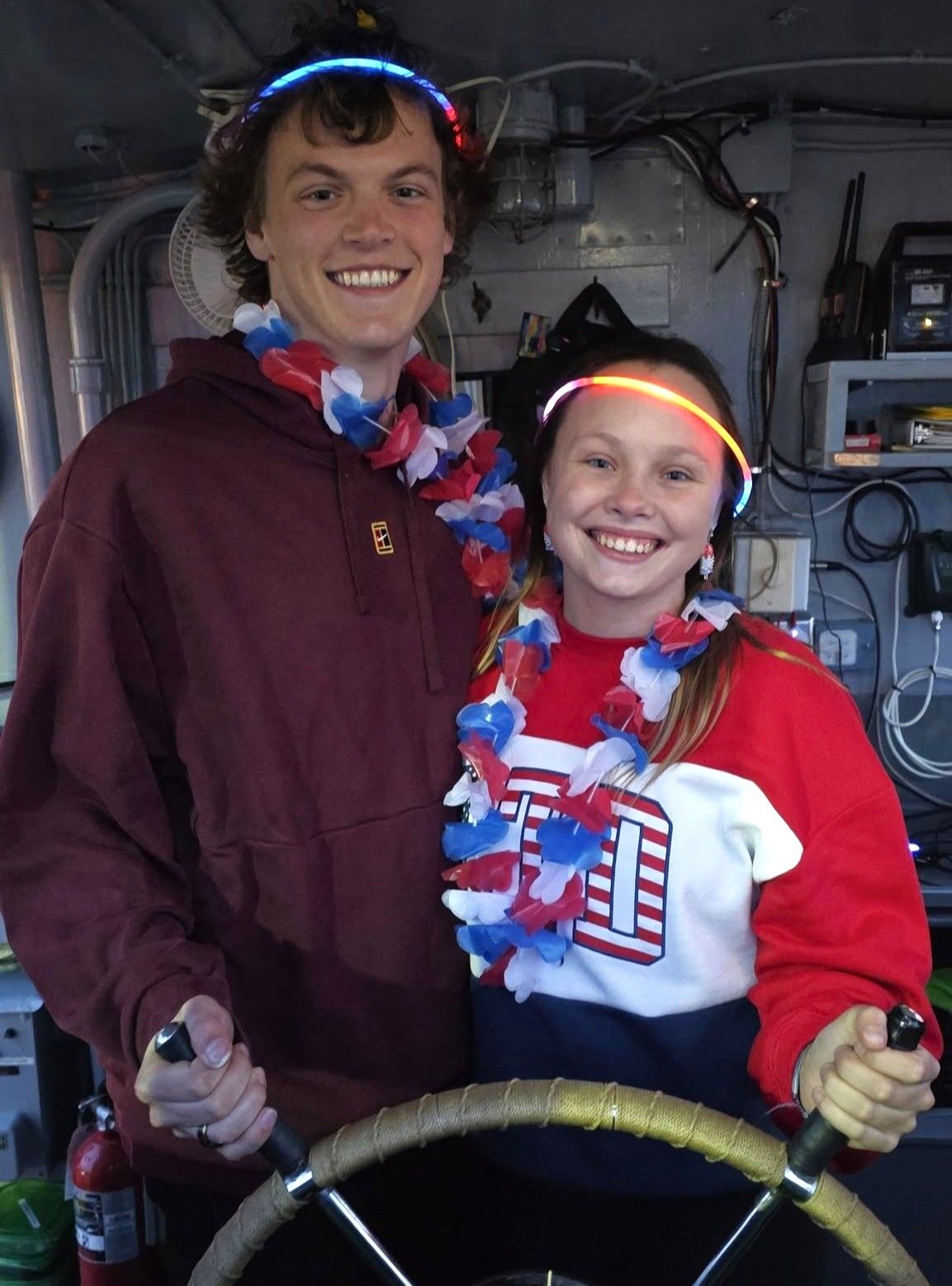 Guest couple posing at the helm in the pilot house for a portrait memento of the Original Soo Locks Boat Tours in Sault Ste. Marie